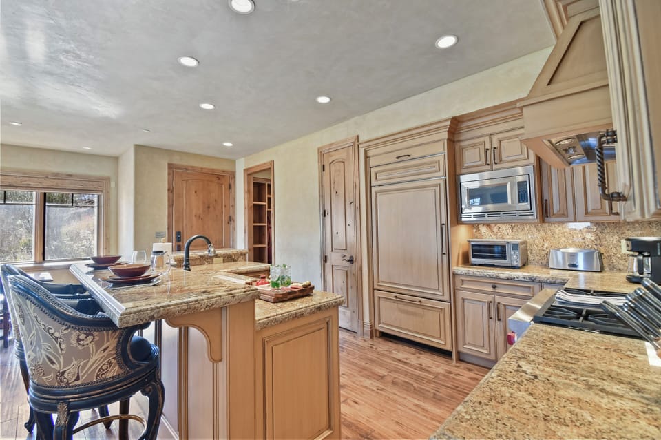 The open-concept kitchen combines custom wood cabinetry, granite countertops, and premium appliances, creating an ideal setting for cooking and entertaining.