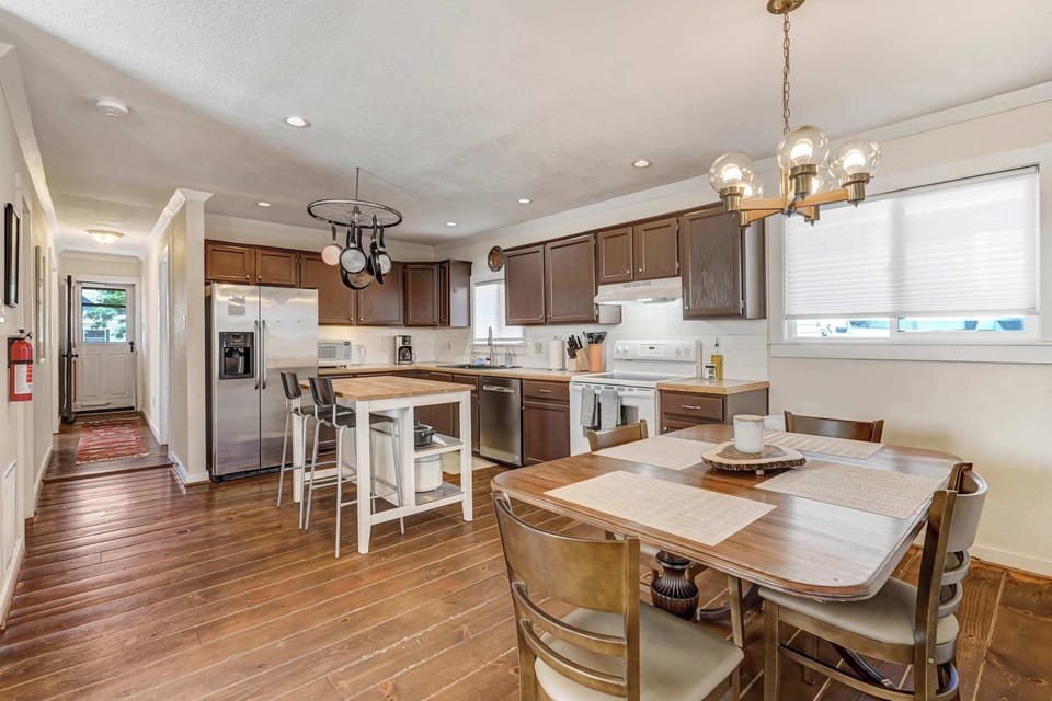 Cook and connect in the light-filled kitchen—pull up a stool at the island or gather at the dining table nearby. Pendant lights, a long run of counters, and warm wood floors set an easy, homey vibe.