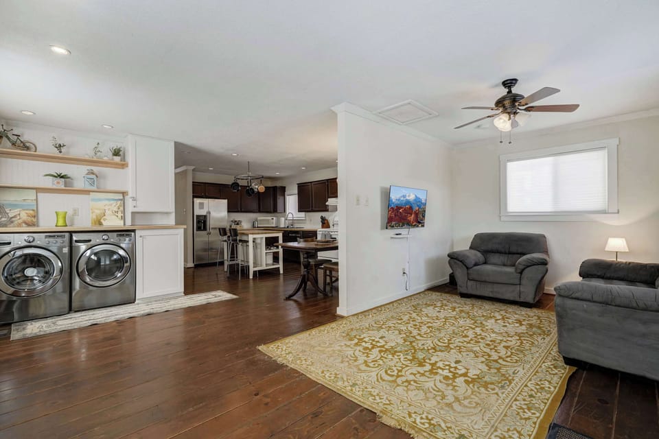 Open living area made for downtime—sink into the gray sectional and stretch out on the big patterned rug. The kitchen is just beyond, with a washer/dryer set along the wall for easy refreshes.