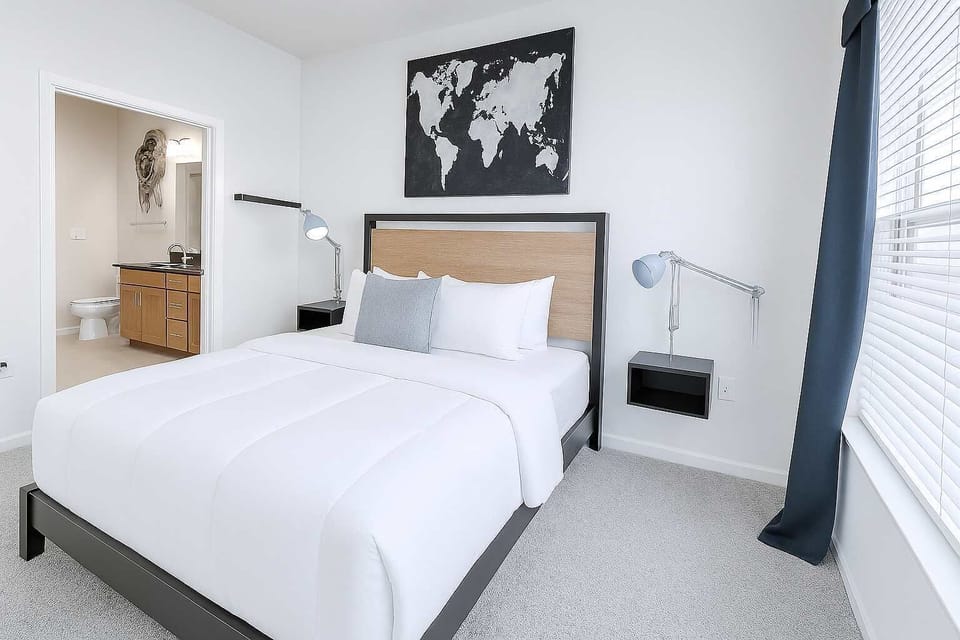 Bedroom with large window, white bedding, and wall painting
