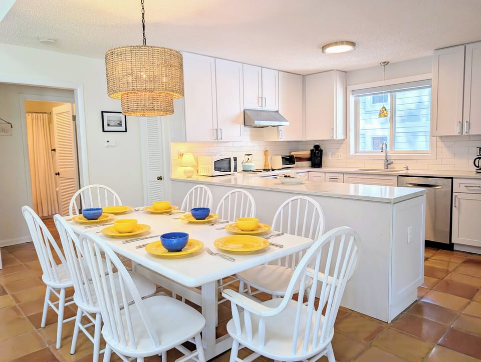 116 Evergreen Road - Kitchen and Dining View with Modern Cabinet - A perspective showing the transition from the dining area to the kitchen, highlighting white cabinetry, stainless steel appliances, and a central breakfast bar.