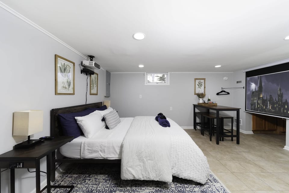 The bedroom features black-out blinds, a projector, Roku soundbar and an 84" screen