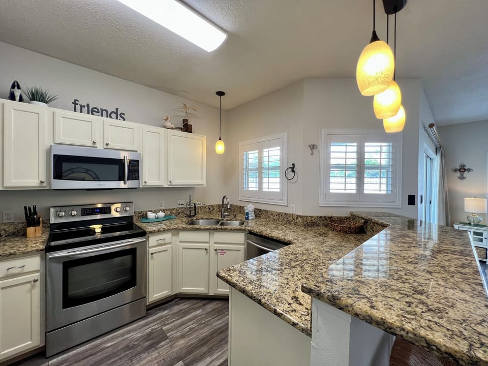 Your fully equipped kitchen features granite countertops, white cabinets, and modern appliances for home-cooked meals during your stay.