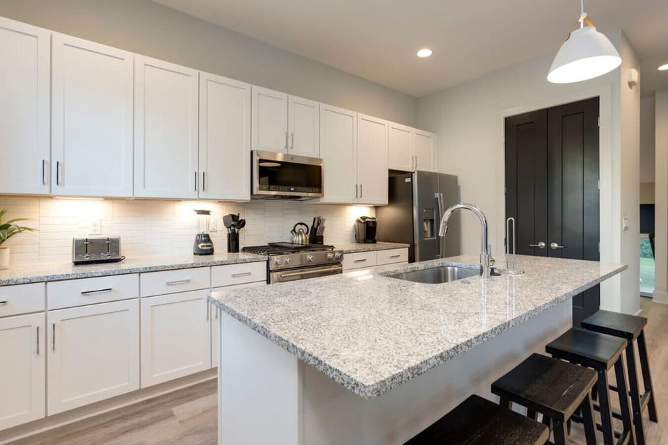A white kitchen from a second angle shows the full island layout and generous prep space.