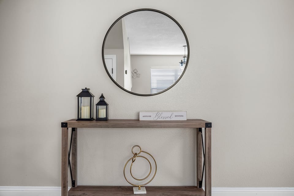 Stylish entry console w/ round mirror and simple, modern decor.