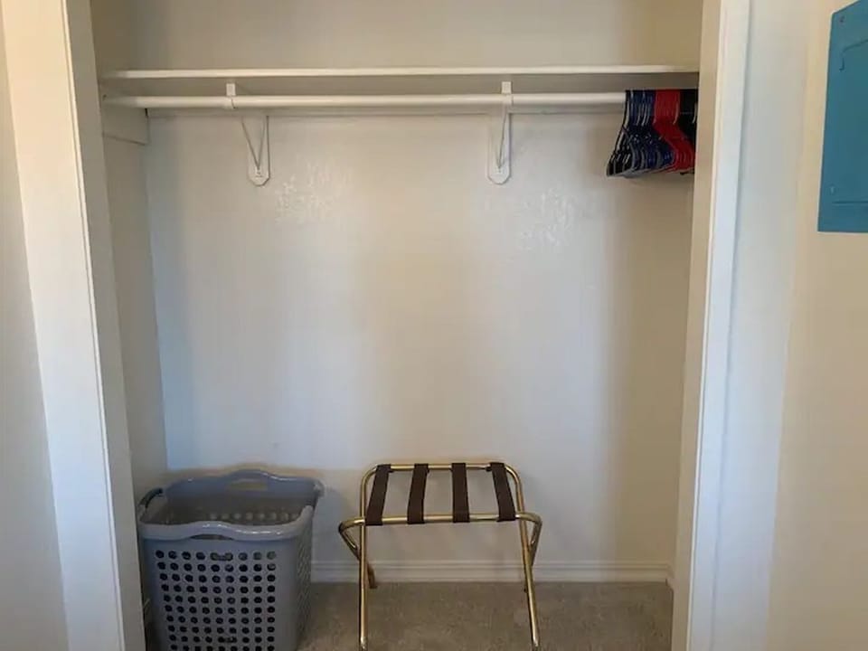 Full closet with laundry hamper and luggage rack. 