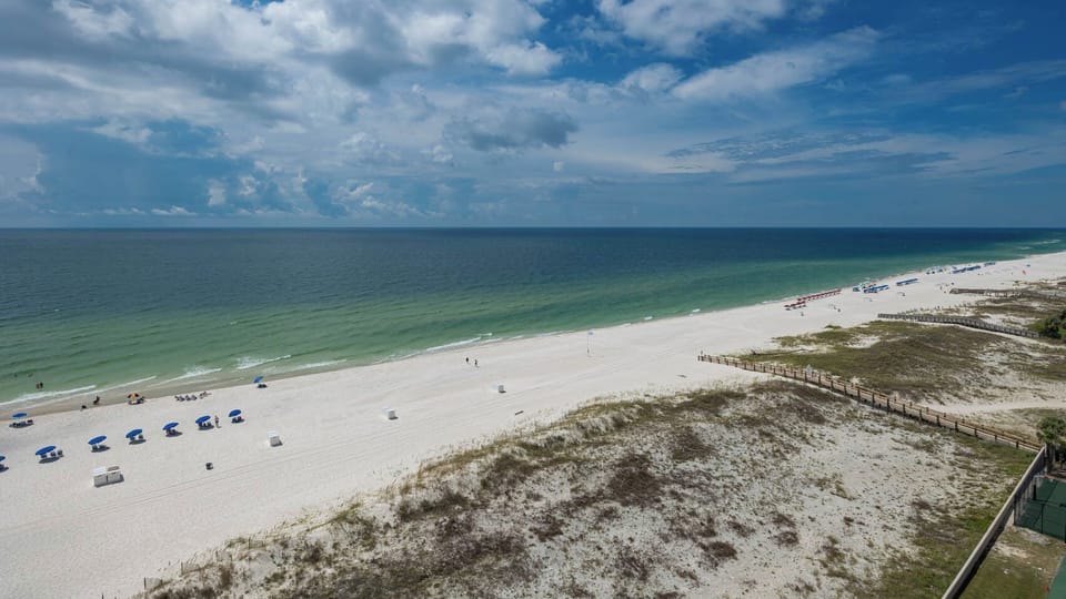 Enjoy the scenic view of the beach with colorful umbrellas and gentle waves, perfect for relaxation and fun