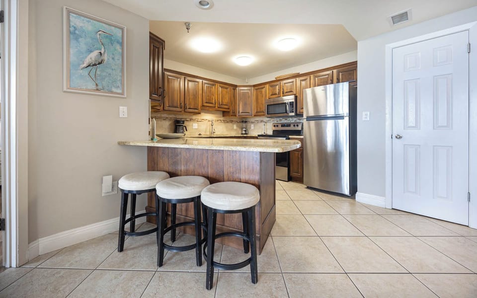 Enjoy casual meals at the breakfast bar, surrounded by warm wood tones and a stylish kitchen