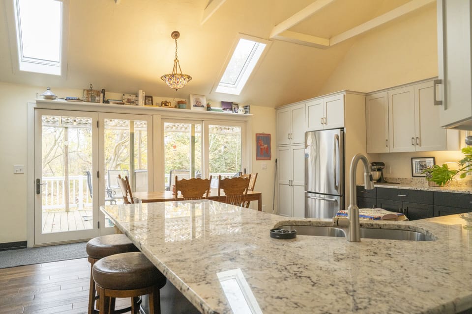 Patio doors off kitchen lead to large deck with grill + dining table. 