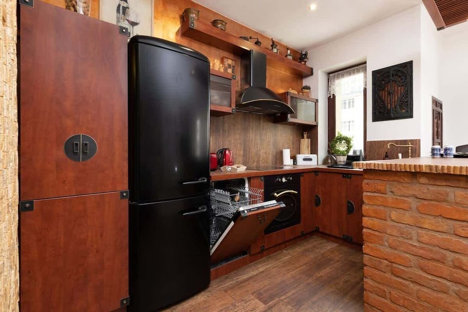 Traditional-style kitchen with wooden cabinetry, a black refrigerator, and vibrant red appliances, including a toaster and kettle.