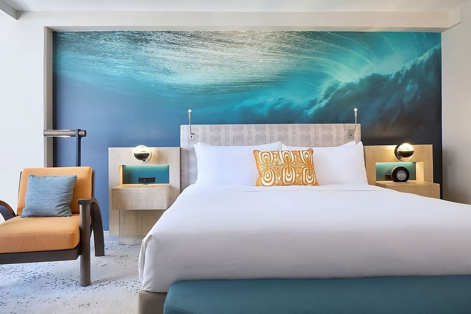 Unwind in a serene room beneath a dramatic ocean mural.