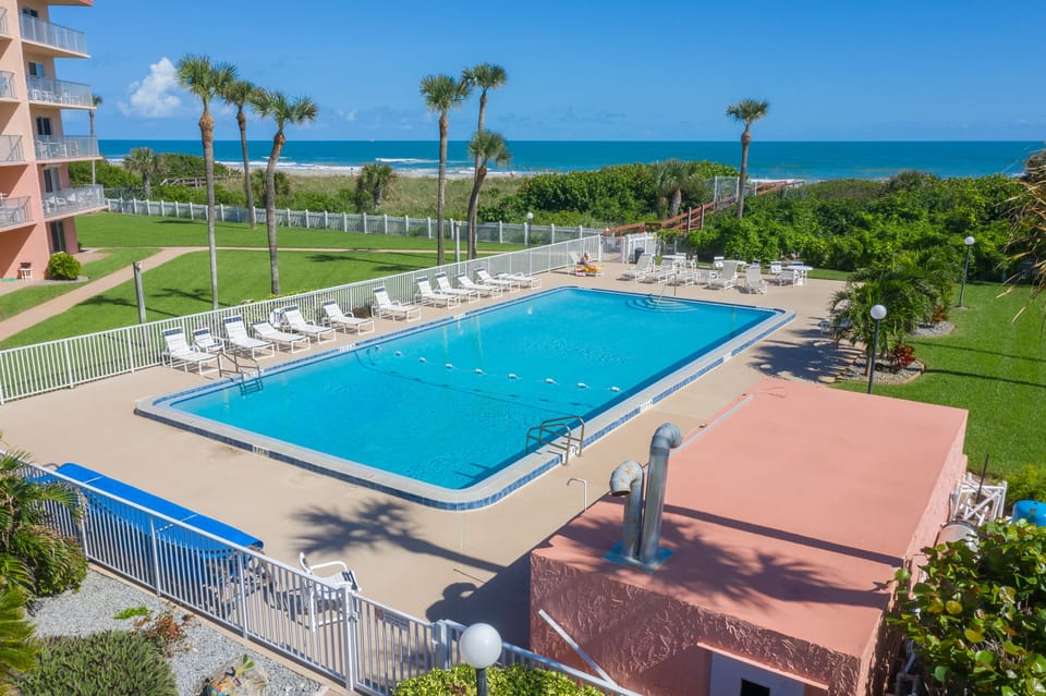 Sparkling blue pool surrounded by palm trees and stunning ocean views