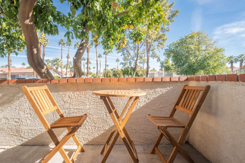 Bistro dining set on front patio shaded by grapefruit tree. 