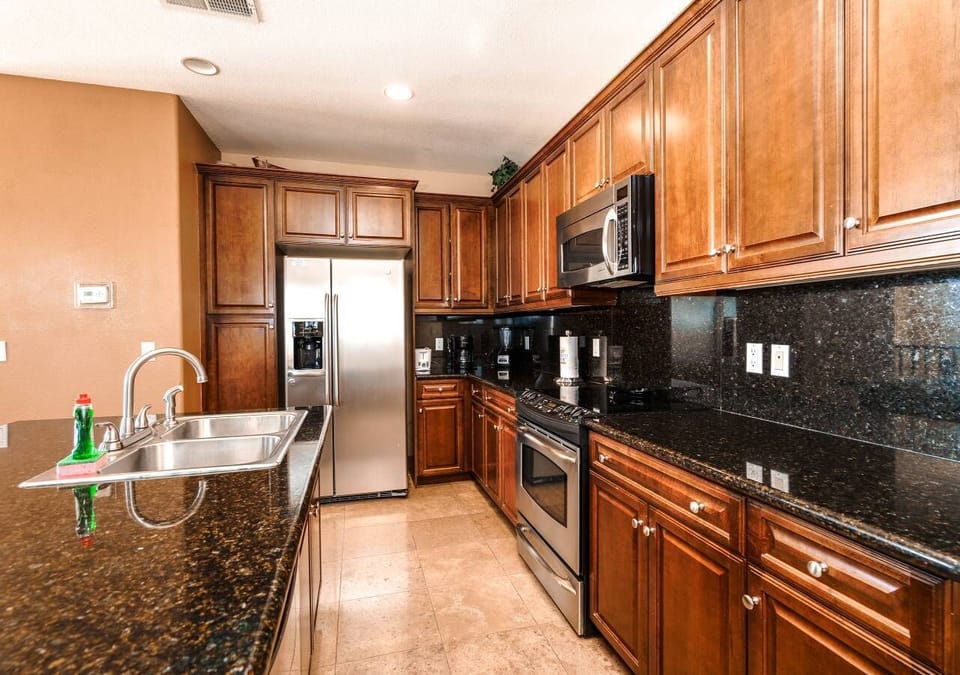 The chef's kitchen is fully stocked with a full-size refrigerator, double ovens, microwave, and cappuccino machine — plus a breakfast bar and patio BBQ overlooking the golf course .