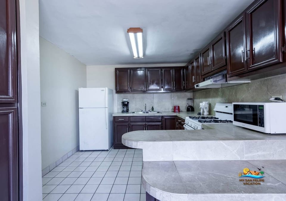 This well-stocked kitchen has a 4-burner stove with oven, microwave, full-size fridge, coffee maker, and dishes for 10 . The open layout flows into the living and dining areas—just steps from the beach