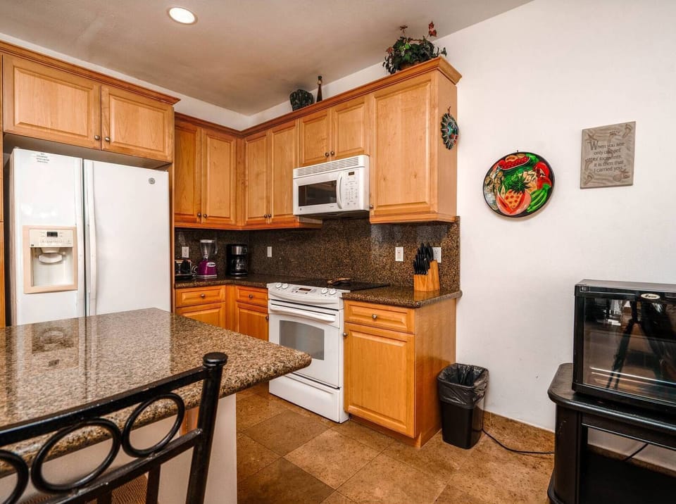 The well-equipped kitchen at Condo 211 includes a full-size refrigerator, microwave, oven, and coffee maker