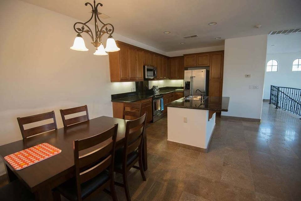 The second floor features an open floor plan with a full kitchen, dining area, and living room — all flowing onto a balcony overlooking the community pool.