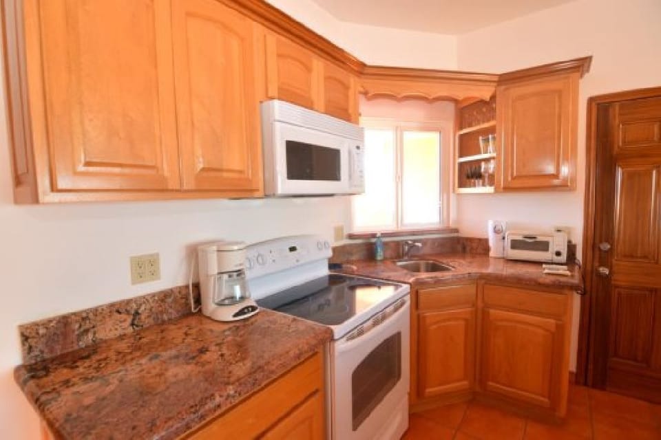 The upstairs kitchen in Condo A is fully furnished with a refrigerator, microwave, dishwasher, stove, oven, toaster, coffee maker, and cookware for group meals