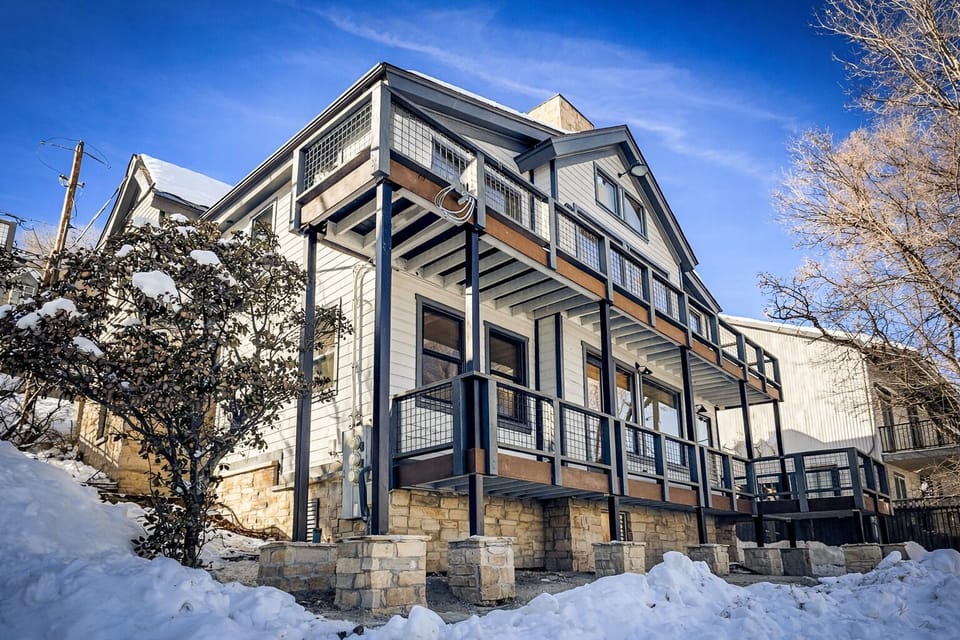 Modern mountain retreat with stone foundation and spacious decks, nestled in a snowy winter landscape.
