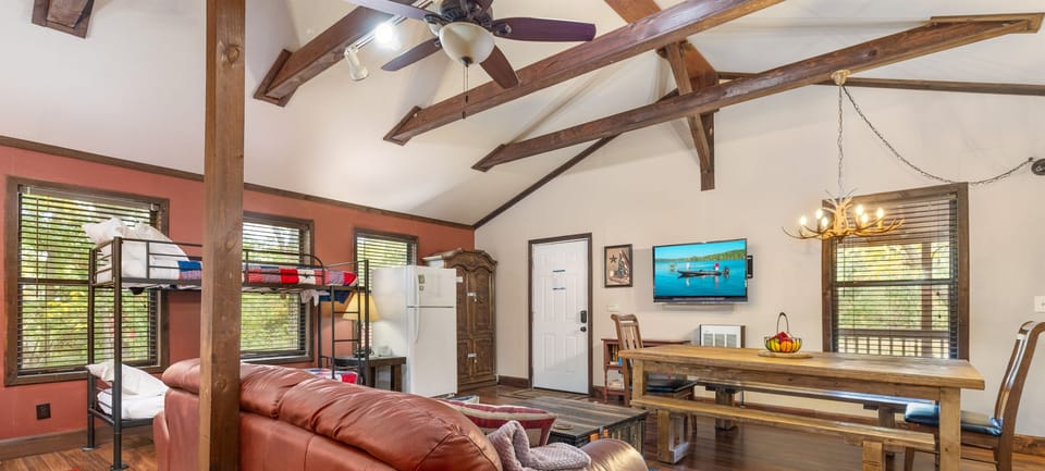 One large room with a full kitchen, large dining table, couch, and beds. 