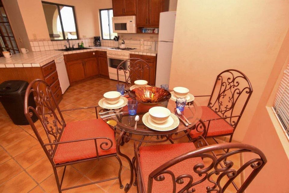 The dining area features a glass table with seating for six, located between the kitchen and living room with direct sightlines to the private pool through large windows .