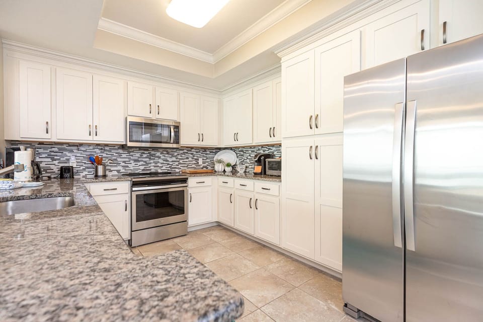 Prepare meals in this kitchen with elegant cabinetry, stainless appliances, and stylish backsplash