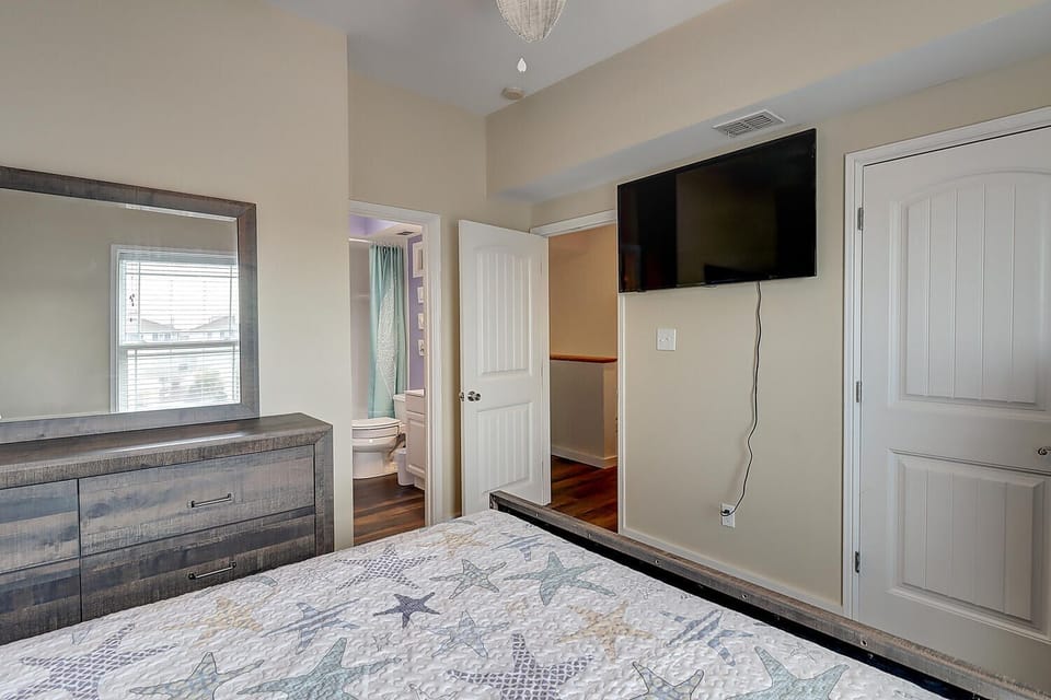 Unwind in your comfortable bedroom featuring a wall-mounted TV, spacious dresser, and convenient wardrobe storage for all your belongings.