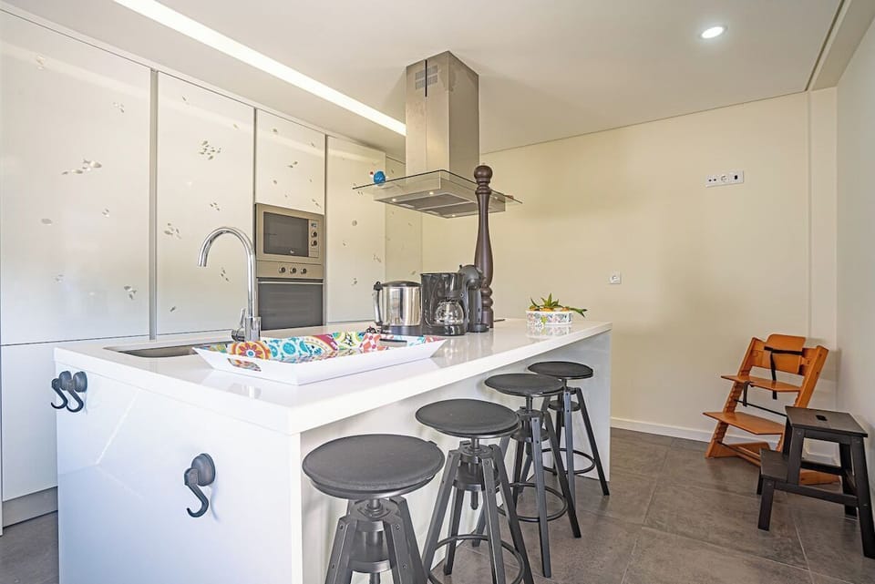 Modern open-plan kitchen with island and bar seating — Villa Sassi, holiday villa in Aroeira