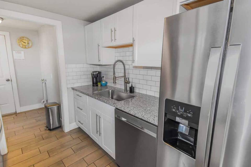 A sleek and modern kitchen with elegant granite countertops, stainless steel appliances, and stylish white cabinetry—perfect for cooking and entertaining!
