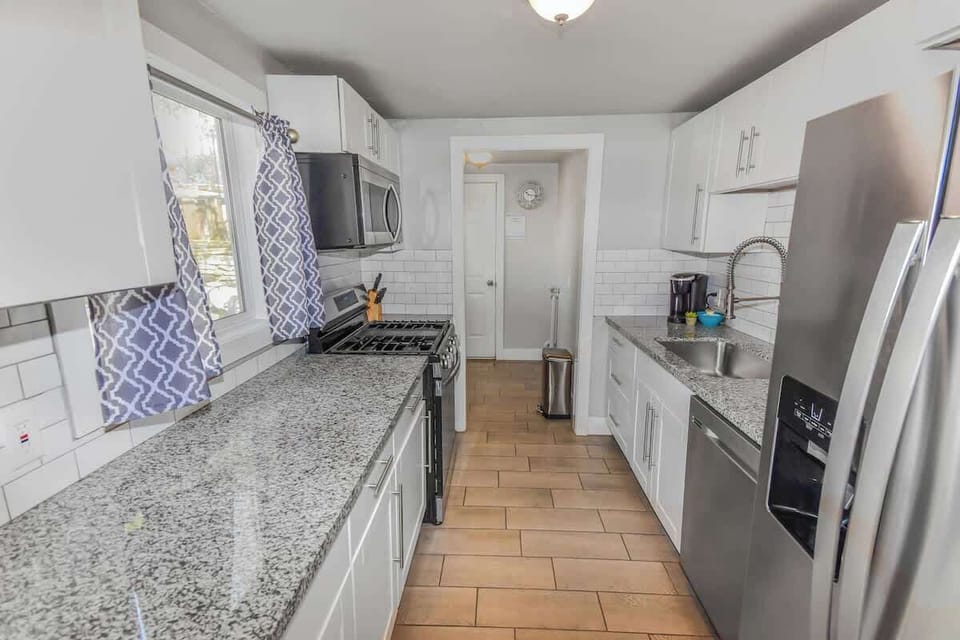 A sleek and modern kitchen with elegant granite countertops, stainless steel appliances, and stylish white cabinetry—perfect for cooking and entertaining!