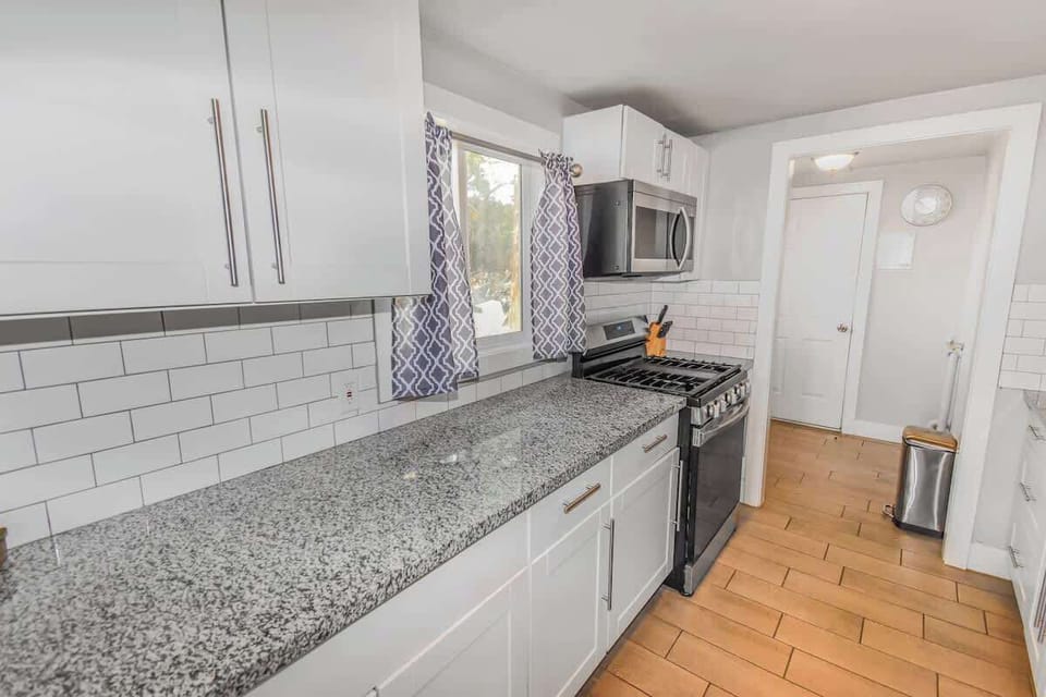 A sleek and modern kitchen with elegant granite countertops, stainless steel appliances, and stylish white cabinetry—perfect for cooking and entertaining!
