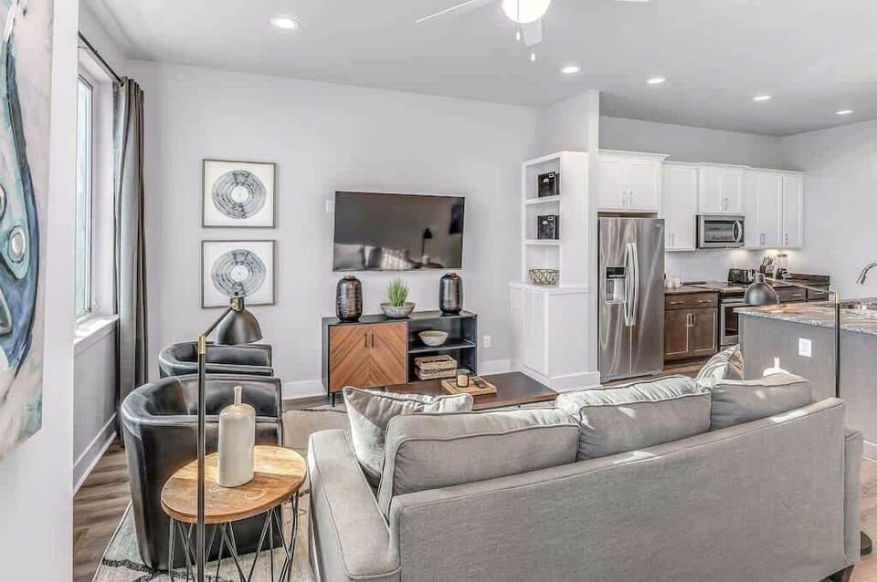 Bright open-concept living room with cozy seating, Smart TV, and a modern kitchen just steps away.