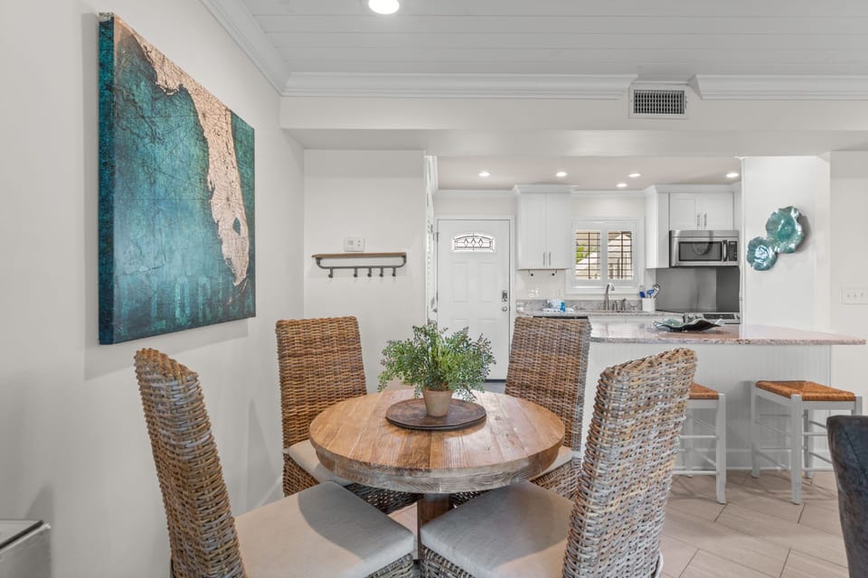 Gather around this inviting dining space where coastal charm meets comfort. The open layout flows seamlessly into your well-equipped kitchen, perfect for preparing meals together and creating vacation memories.