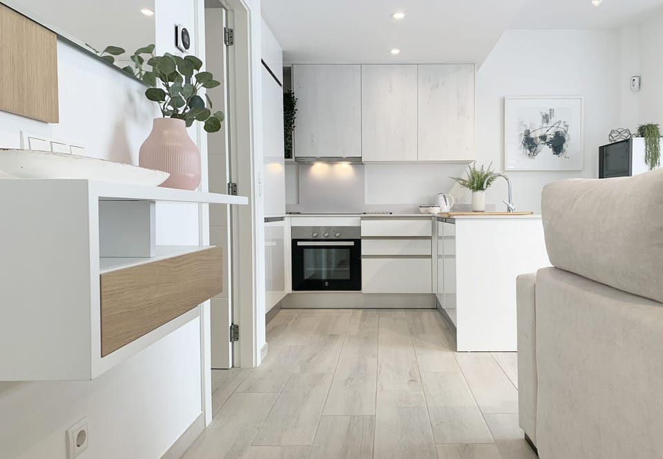 Well-lit kitchen, equipped with stove, refrigerator and storage