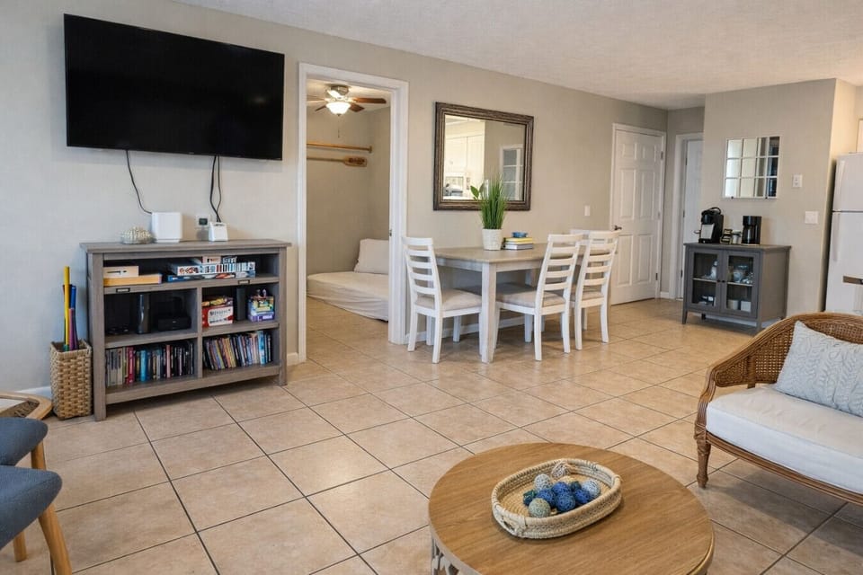The dining area has a large table with a bench seat and chairs, and four bar stools provide additional seating.