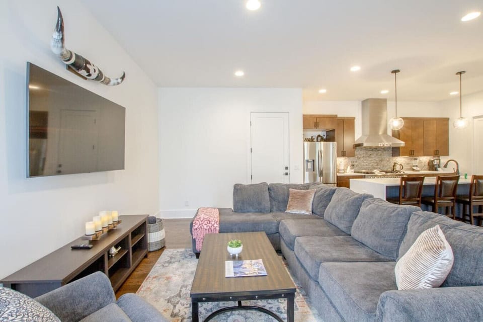 A comfortable living area with a plush sectional, TV, and warm wood tones is ready for group nights in.