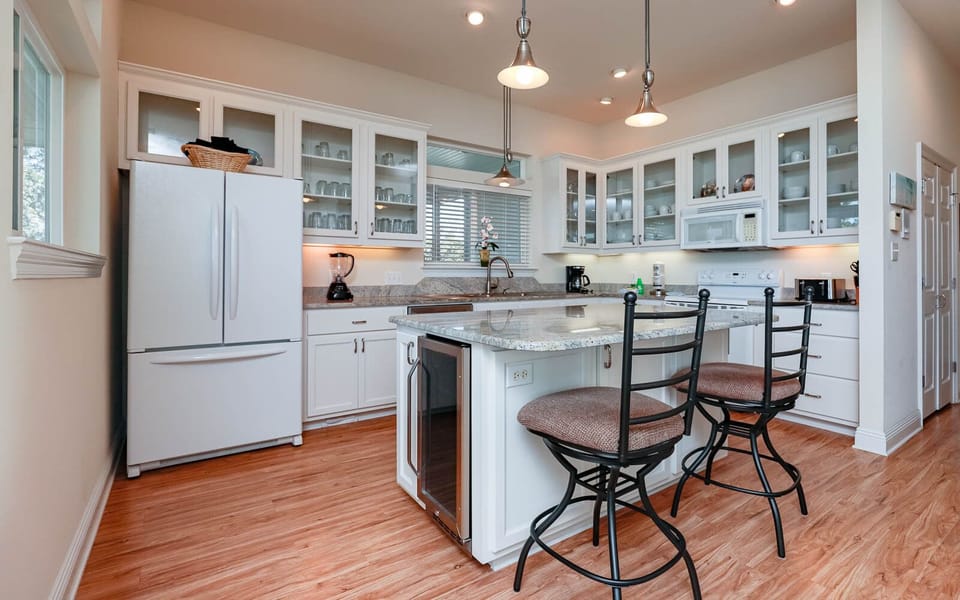 This kitchen features sleek white cabinetry, granite countertops, and a cozy breakfast bar, perfect for casual dining