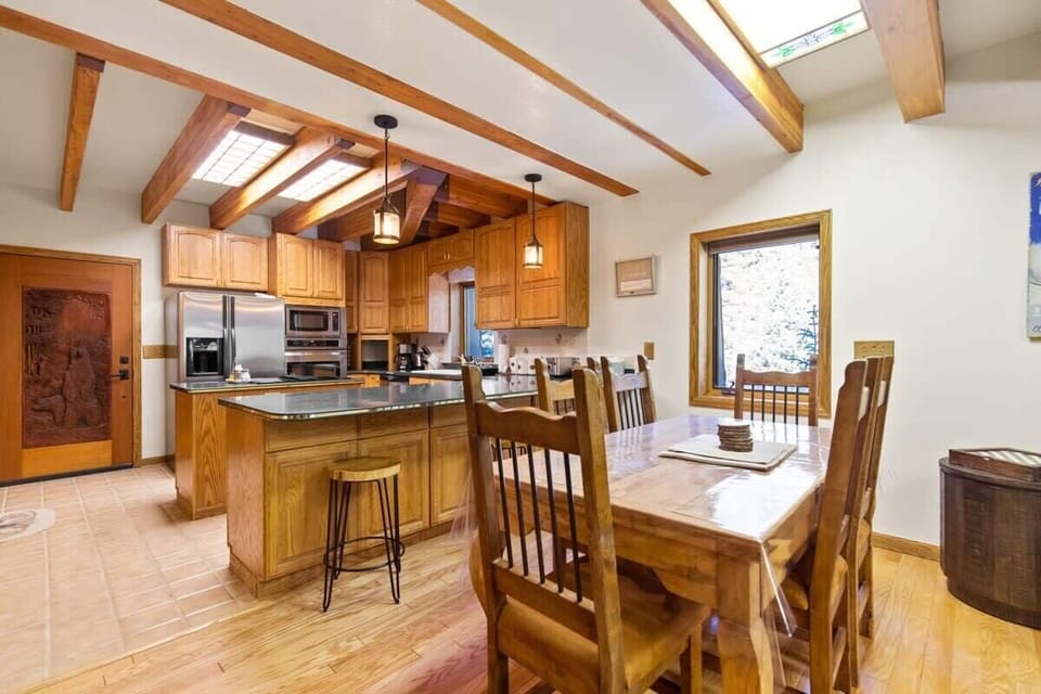 The open concept layout allows easy access between kitchen and dining area, where you can seat six around this classic wood dining table and have the option for three more to join in at the adjacent bar.