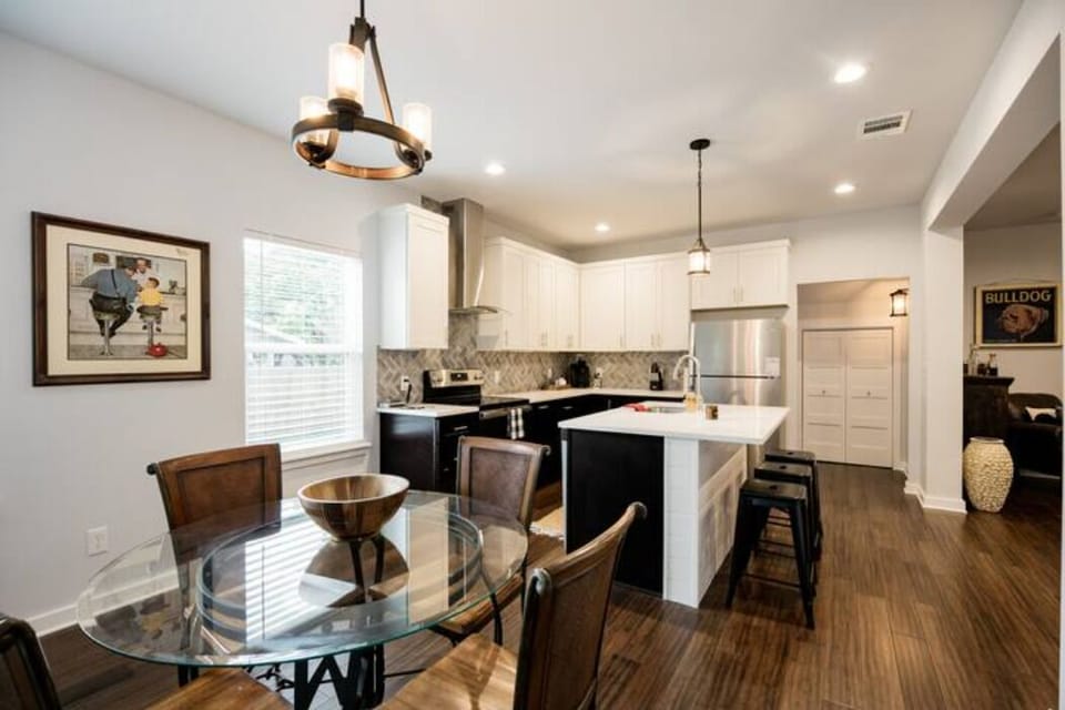 Kitchen has a table w/ 4 chairs and 3 barstools