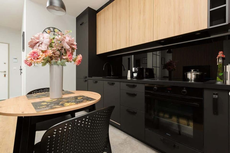 A small dining space with a black table and two chairs. The table is elegantly set with flowers and tableware