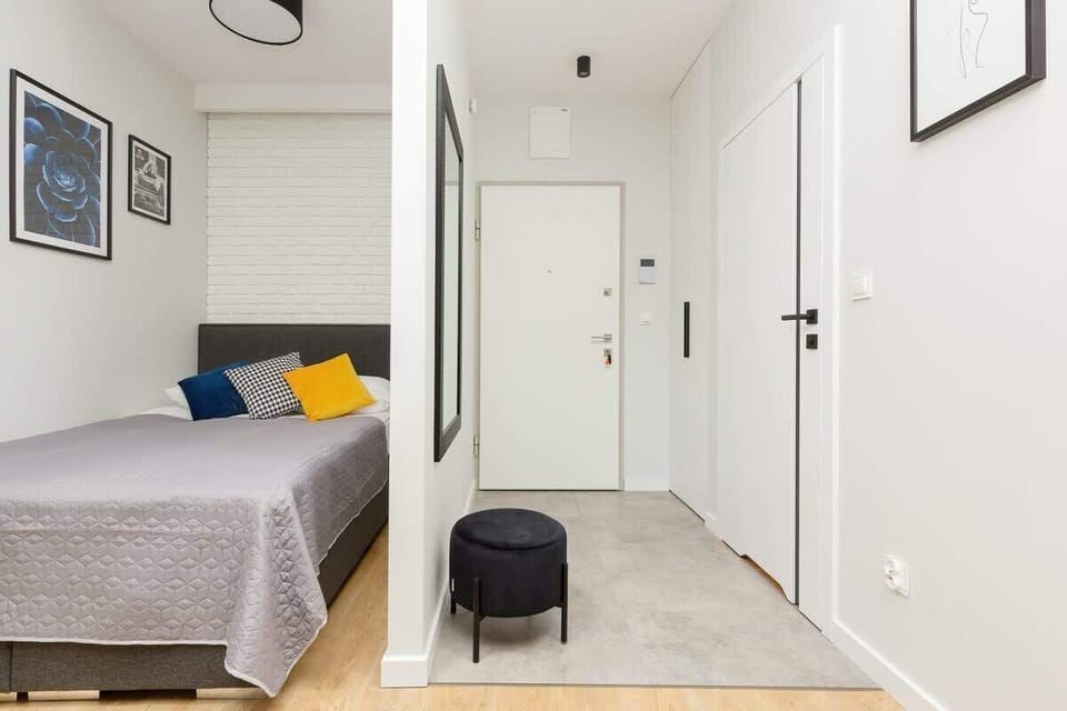 A cozy bedroom featuring a double bed with white and yellow bedding, complemented by soft lighting. A large mirrored wardrobe adds both style and practicality to the space.