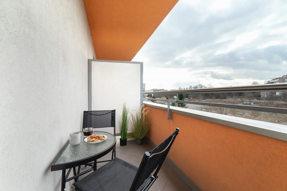 A spacious balcony with outdoor furniture and a view of the surrounding neighborhood.