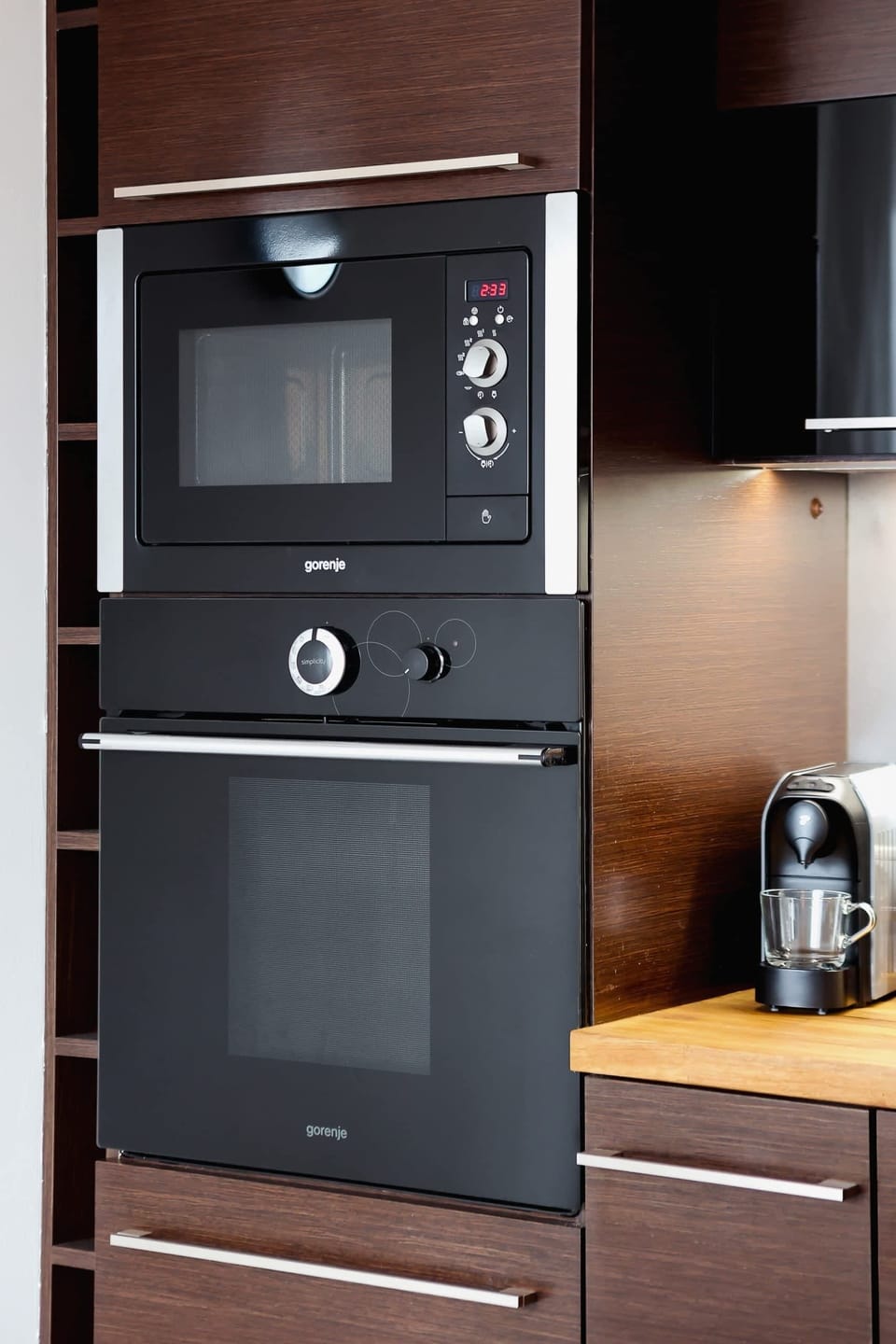 A close-up of the kitchen, highlighting the refrigerator and ample pantry storage in sleek, dark cabinetry.