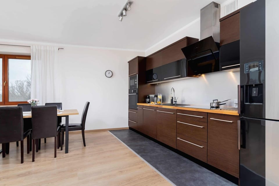 A combined dining and kitchen space with a dining table set for four and modern cabinetry in a sleek black finish.