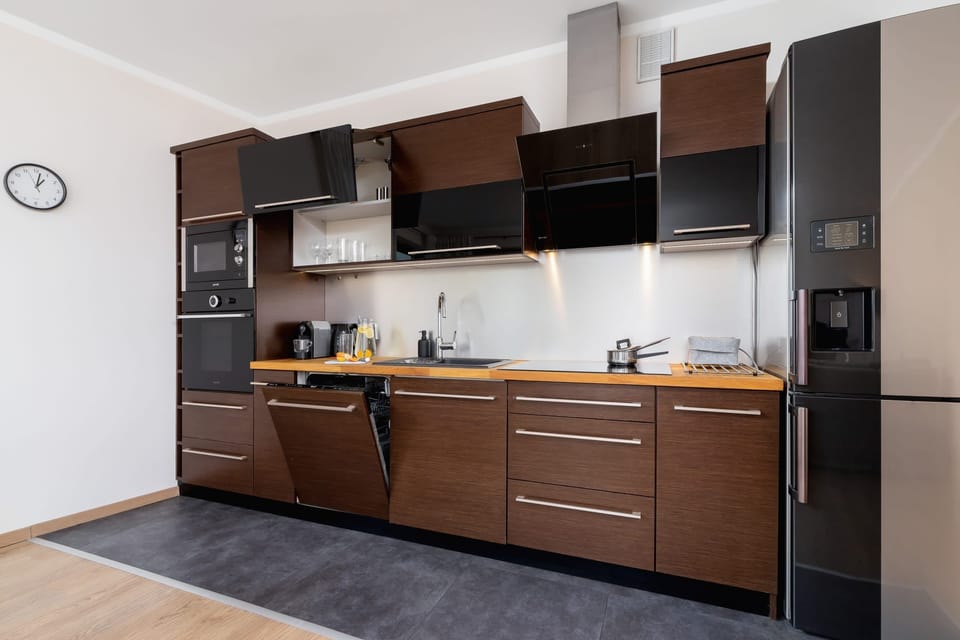 A compact but modern kitchen with wooden cabinets, black countertops, and integrated appliances.