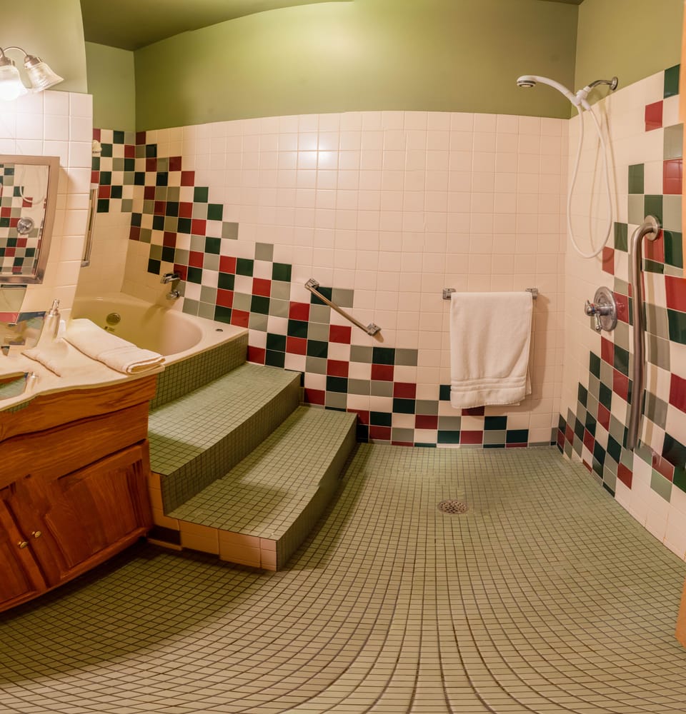 tiled bathroom with two showers and deep tub