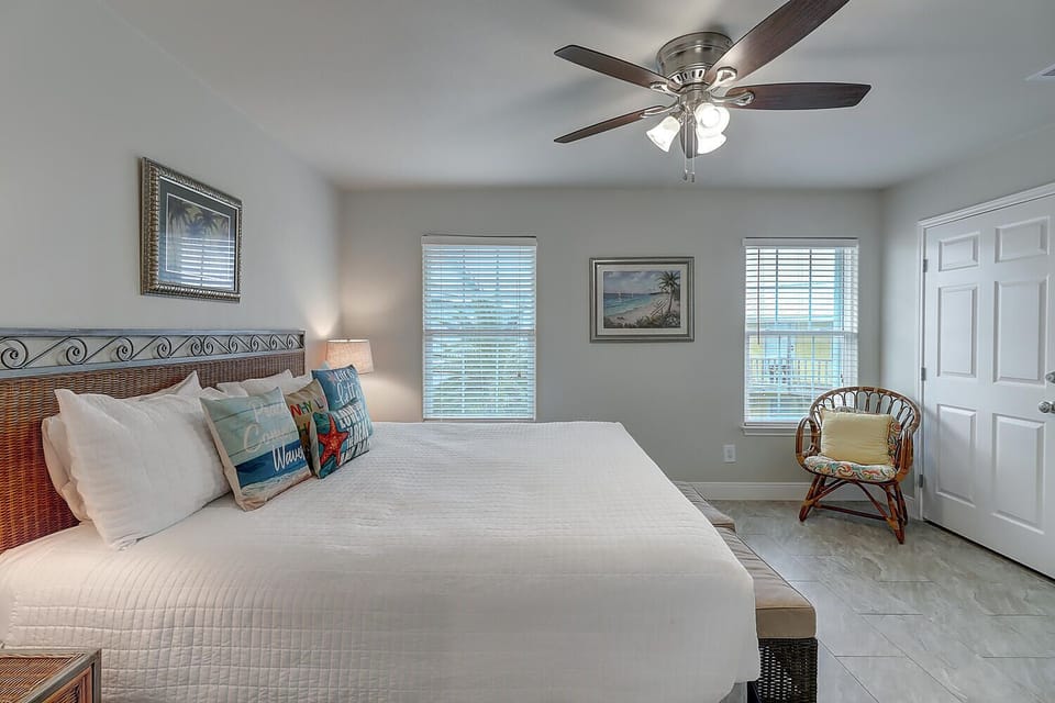 Drift off in your serene bedroom featuring coastal art, a gentle ceiling fan, and wicker touches that create the perfect beachside retreat.