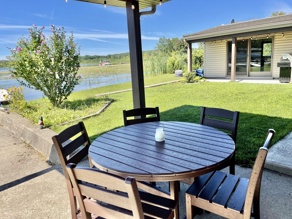 Patio dining area with lake side smokeless fire pit in background 