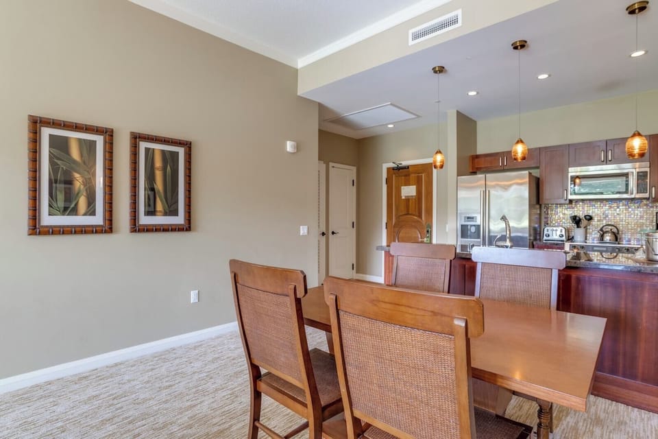 Stylish dining area beside modern kitchen with pendant lighting accents.