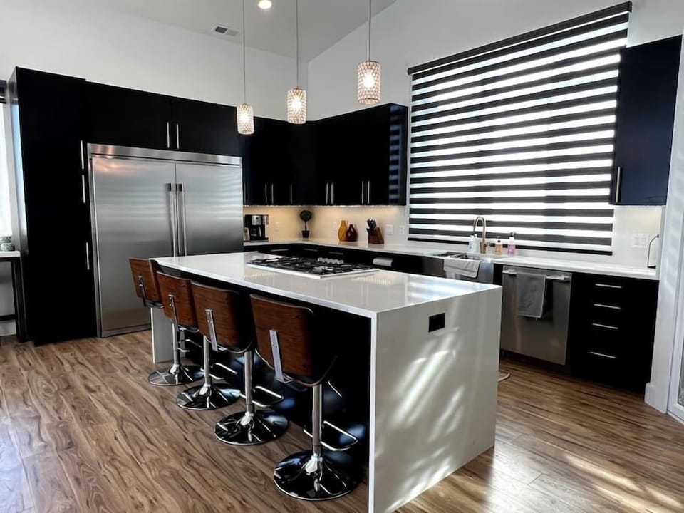 Kitchen view of double Fridgidaire and large island bar with Thermador 5 burner cooktop. on Quartz countertops